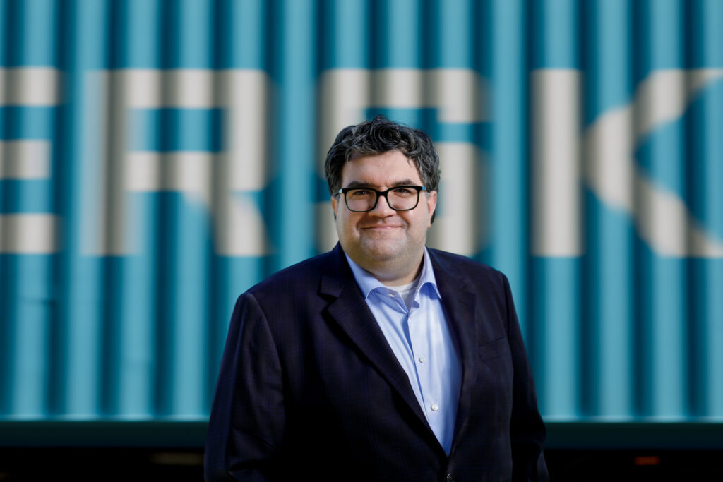 Chuck Giroux editorial portrait beside blue shipping containers, Wando terminal Charleston