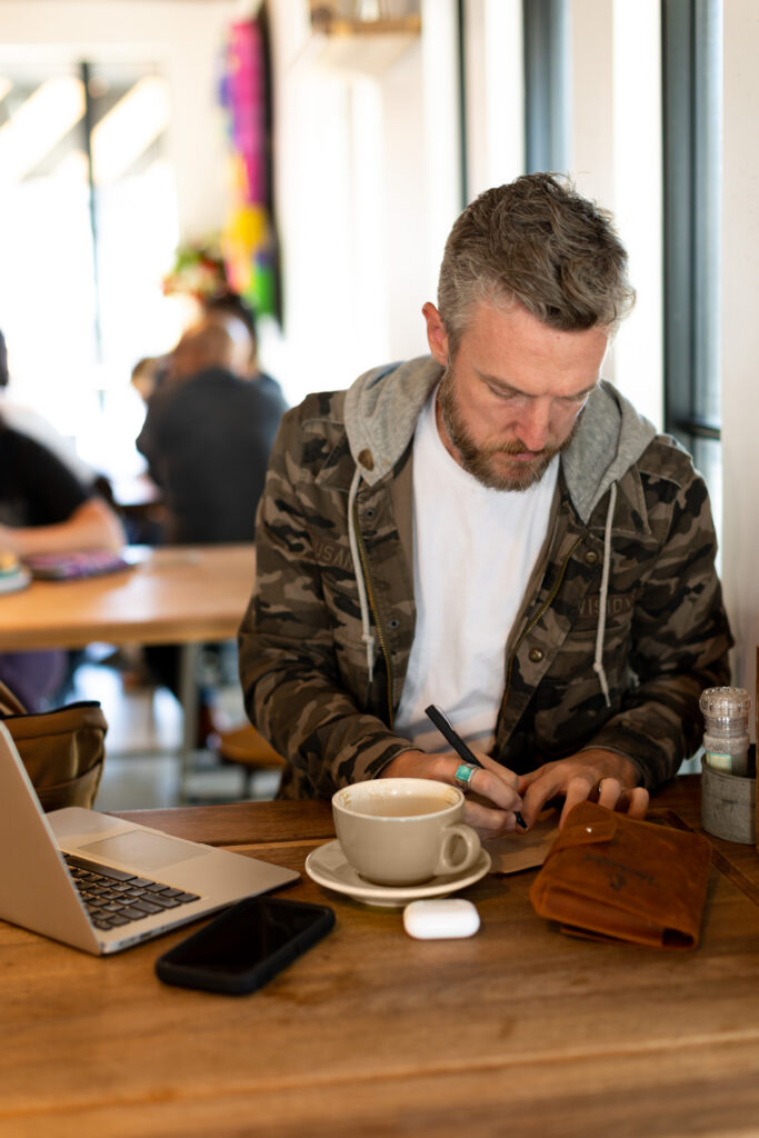 Nate Davis working at a laptop in a Charleston coffee shop during a brand photography session